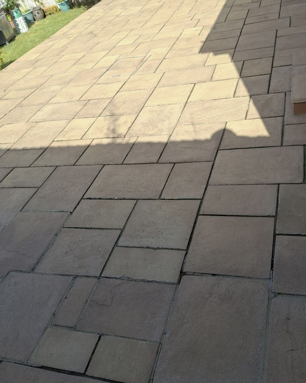 Patio halfway through pressure washing, showing cleaned and uncleaned slabs either side of a clear line