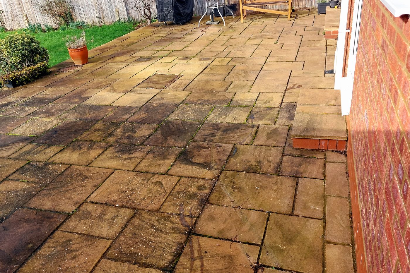Patio covered in algae, moss and black staining before pressure washing